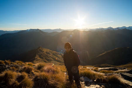 A young Asian man with sunglasses enjoying a stunning scenery of alps on the high mountain before sunset in a beautiful blue sky day.の写真素材