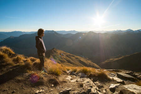 A young Asian man enjoying looking at the stunning scenery on the high mountain before sunset.の写真素材
