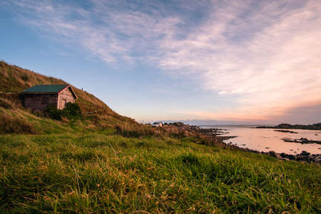 Beautiful scene of a landscape in a rural area beside the ocean at sunset. Cosy Nook, New Zealand.