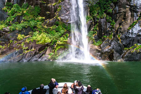 2018, April 18 - New Zealand, Milford Sound, A group of tourists enjoying a stunning scene of nature while cruising into waterfall in Milford Sound, New Zealand.のeditorial素材