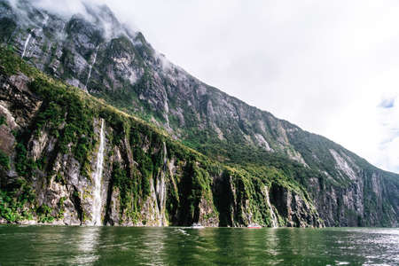 A stunning scene of nature with many waterfalls from the high mountain at Milford Sound, New Zealand.の写真素材