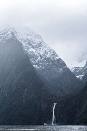 A stunning scene when a ferry cruising to a waterfall at Milford Sound, New Zealand.の写真素材