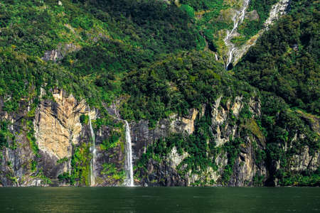 A stunning scene of nature with many waterfalls from the high mountain at Milford Sound, New Zealand.の写真素材