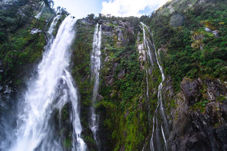 A stunning scene of nature with many waterfalls from the high mountain at Milford Sound, New Zealand.の写真素材