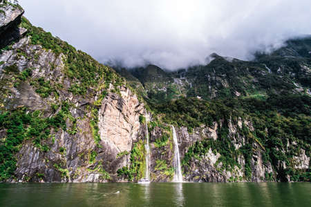 A stunning scene of nature with many waterfalls from the high mountain at Milford Sound, New Zealand.の写真素材