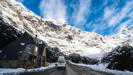 The stunning scenery of a rocky mountain and trees covered with a white snow. A road to Milford Sound. A filmed while driving.のeditorial素材