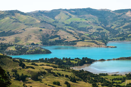 Beautiful landscape of a peninsula. cloudy sky fresh ocean and grassland mountain. New Zealand agriculture.の写真素材
