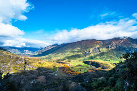 Stunning landscape view of green grass field and snow mountain in autumn on a cloudy day. Diamond lake track, Wanaka, New Zealand.の写真素材