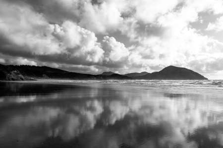 Wharariki Beach with and wave and cloudy. Black and white photo style.