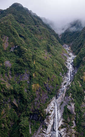 A beautiful glacier waterfall falling from high rocky mountains.の写真素材