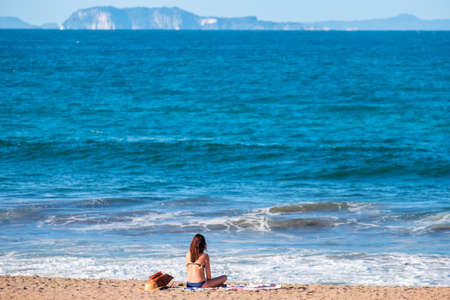 A bikini girl doing meditation and enjoying next to the ocean. Peaceful concept..の写真素材