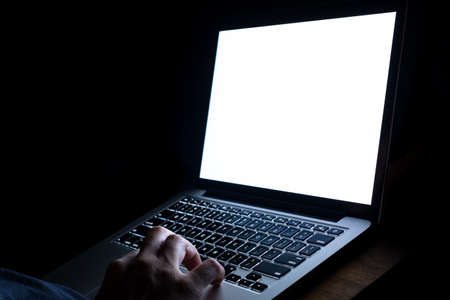 A man hand using laptop with blank screen at night. bedtime working concept..
