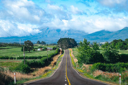The beautiful view of Mount Taranaki covered with a cloud and fog after raining. Landscape in the rural area with Highway and beautiful nature. New Plymouth, New Zealand.の写真素材
