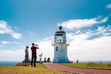 2019 February, 24th, New Zealand, Northland, Cape Reinga - People visit the heritage lighthouse and the most northern point in the country. The beautiful scenery of the landscape with ocean and blue sky.のeditorial素材