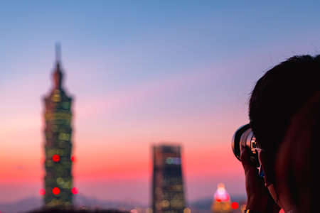People are taking photo. The dusk scenery cityscape, Taipei 101 Observatory tower, and other buildings, Taiwan. View from Xiangshan (Elephant Mountain).の写真素材