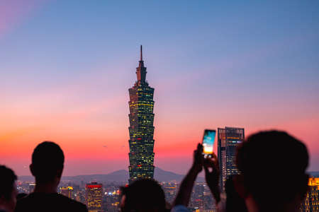 People are taking photo. The dusk scenery cityscape, Taipei 101 Observatory tower, and other buildings, Taiwan. View from Xiangshan (Elephant Mountain).の写真素材