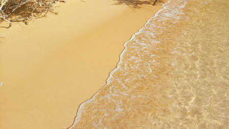Golden sand on the beach with ocean waves.の写真素材
