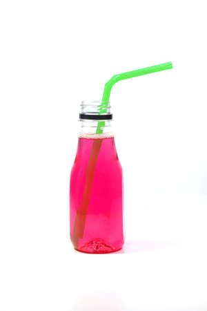 The reddish-pink colored water is packaged in a clear plastic bottle. with green drinking strawの写真素材