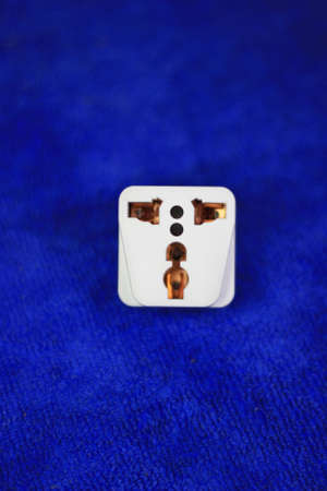 white plug adapter for travel on a blue background of microfiber cloth