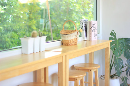 Picnic baskets, cacti and books are placed on wooden tables in the cafe to decorate. The wall of the shop is glass.の写真素材