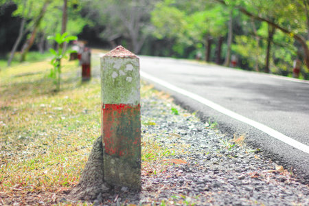 Red and white cement pillars prevent road hazards The background is natural bokeh.の写真素材