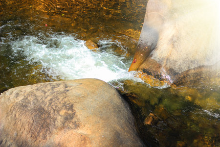 Mountain Stream Flowing Between Two Boulders Forming a Small Waterfall.の写真素材