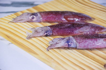 Three Squids Lined Up on Wooden Surface Shot from Slightly High Angle