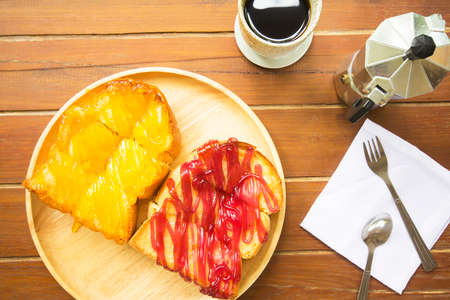 Pitch bread with jam, strawberry jam, pineapple and hot coffee on wood.の写真素材