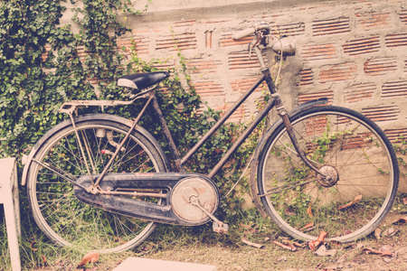 Old bike leans against an old brick wall, vintage background.の写真素材