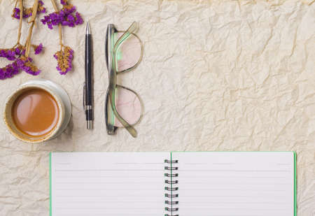 Notebook office with a blank page in the box office with a  camera, a pen,  and purple flowers. Top view crumpled paperの写真素材