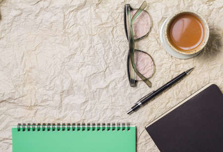 Cup coffee, glasses, pencil on notebook paper background.