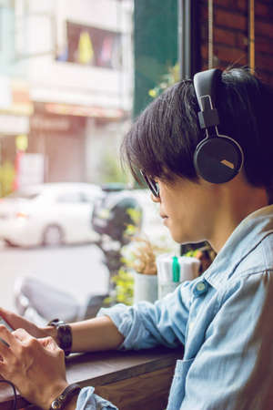 Teenagers sitting headphones and listening to music in sun light and vintage toneの写真素材