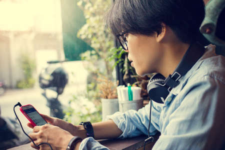 Man wearing headphones sitting on the phone with light Sunset.の写真素材