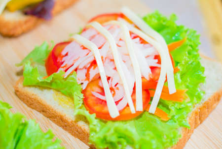 Sandwich with lettuce and crab sticks, cheese on the wood.の写真素材