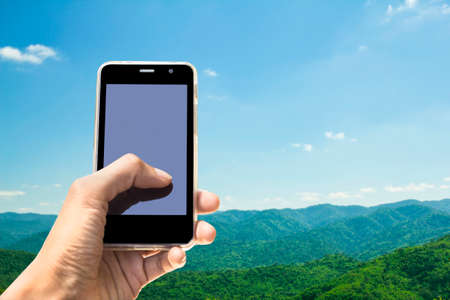 Hands Mobile Phone and mountains nature background.の写真素材