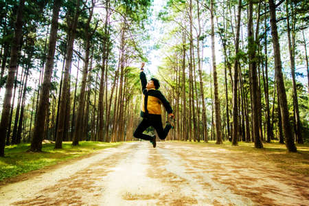 People jumping in forest trees sun light background.