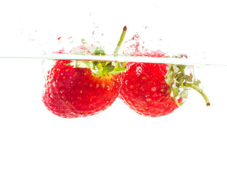 Throw the strawberries into water on white backgroundの写真素材