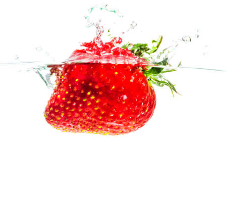 Throw the strawberries into water on white backgroundの写真素材