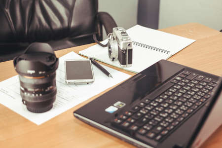 Mobile phone, camera film, pen and a computer on my desk.の写真素材