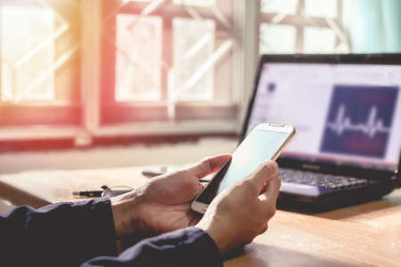 working on phone and computer with sunset business concept background.の写真素材