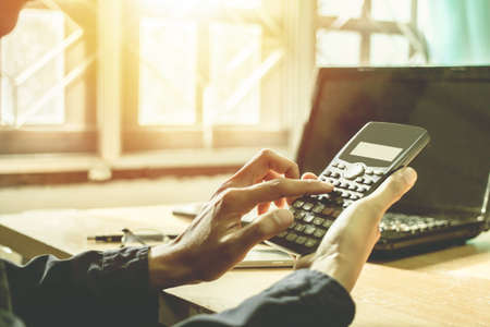 working on calculator and computer with sunset bussiness concept background.の写真素材