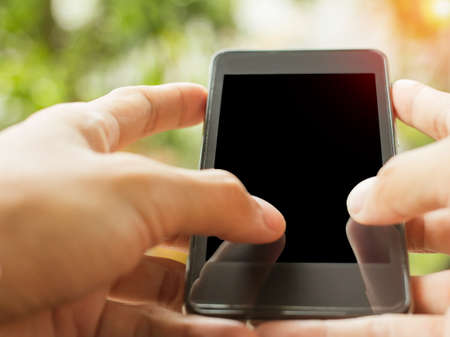 Close up of hands holding telephone copy space with sunset background.の写真素材