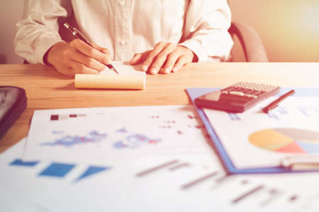 Businessmen are writing books and exhibiting charts and graphs to work.の写真素材