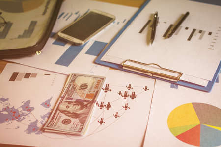 Charts and graphs of the work are US bank notes (US Dallas) put on the desk.の写真素材