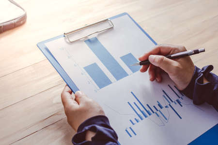 businessman holding a pen and  reports The graph shows