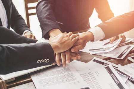 Close up hands of young Asian business team. Online Trading Graphs placed on a wooden table.
