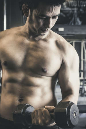Asian man raising Dumbbell  Black color has handsome body good healthy Indoor exercise in gym.の写真素材