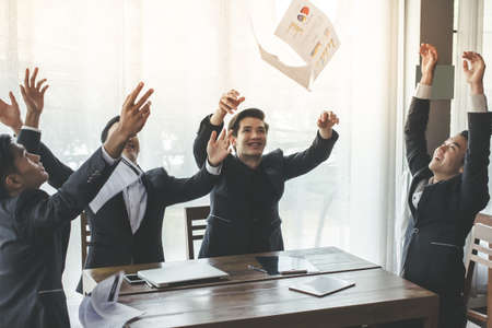Asia business people throwing paper teamwork They smile sitting on chair at the office with her colleagues Job successの写真素材