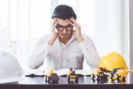 Asian handsome young man Engineering sitting stress with work on the table in roomの写真素材