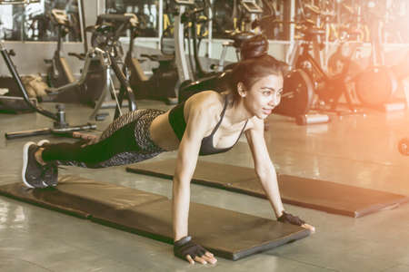 Young asian woman doing push up exercises at gym Fitness Sport exercising concept with light sunsetの写真素材